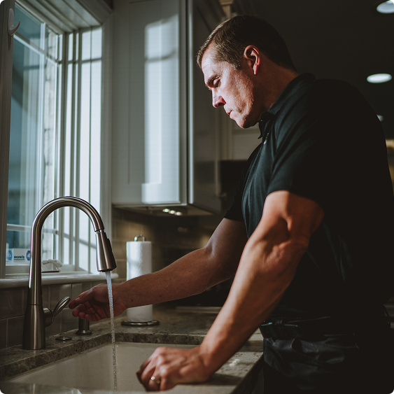 Drake Heating & Air plumber running water to test a repaired kitchen faucet