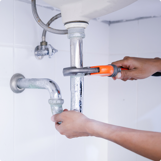 Close-up of hands tightening a P-trap under a sink with a wrench