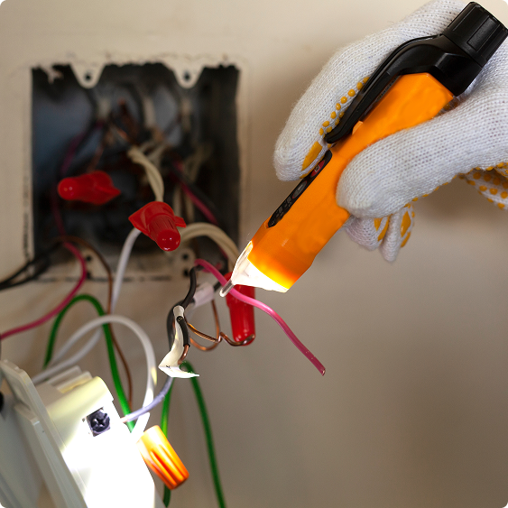 Gloved hand securing wire connectors inside an electrical box