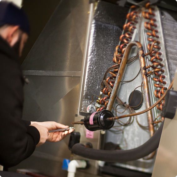 Technician servicing the copper coils inside a furnace during a heating repair