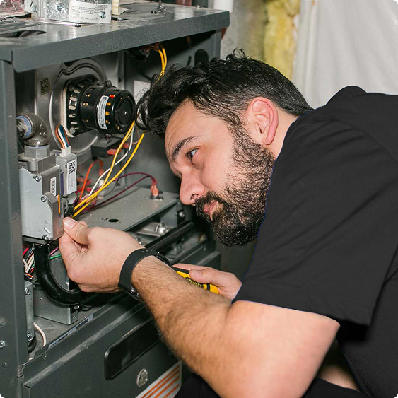 Drake Heating & Air technician working inside a furnace control panel